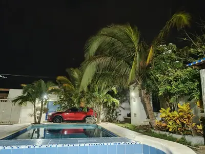 a red car parked in front of a house with palm trees at Cabaña campestre Villa Liliana in Juan de Acosta