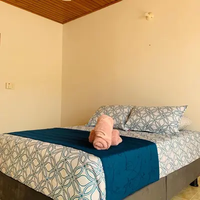 a bed with a blue comforter and two towels at Hostel Cerca al Centro Histórico in Cartagena de Indias