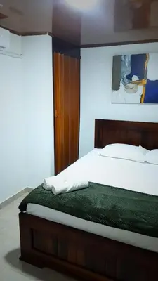 a bedroom with a large bed with a wooden headboard at Hospedaje san gabriel in Barranquilla