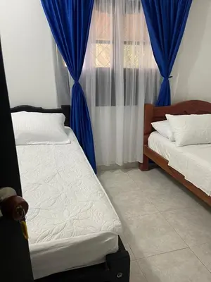 a bedroom with two beds and a window with blue curtains at Mediterráneo Relax in San Antero