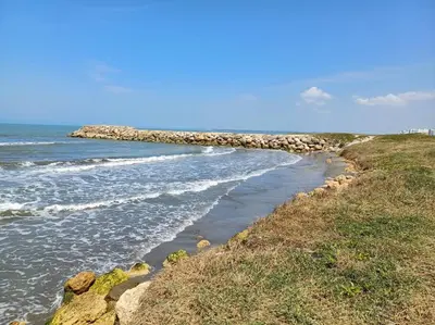a beach with rocks and the ocean on a clear day at New Apartment very close to Airport and beaches in Cartagena de Indias
