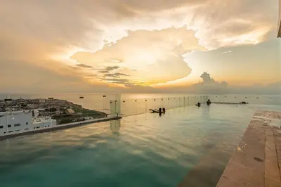 a infinity pool on the roof of a building with a sunset at Awesome View Historic Center, Castle and Sea 2BR in Cartagena de Indias