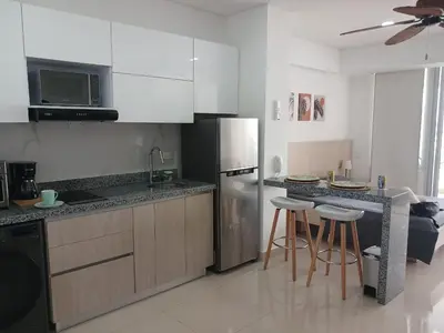 a kitchen with a stainless steel refrigerator and bar stools at Cartagena Beach Resort cerca al aereopuerto in Cartagena de Indias