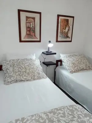 two beds in a bedroom with two pictures on the wall at Hostal CORALES in Tolú