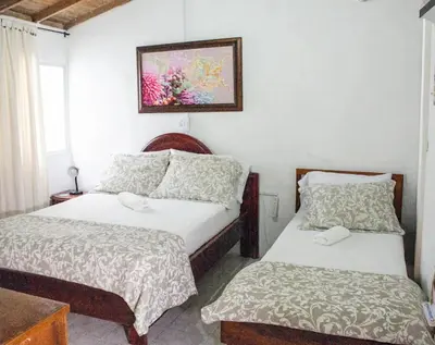 a bedroom with two beds and a picture on the wall at Hostal CORALES in Tolú