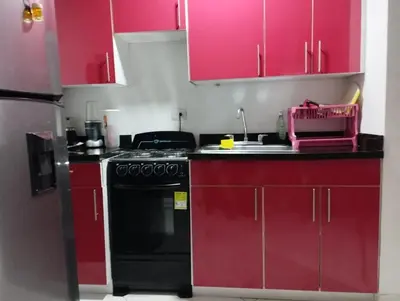 a kitchen with red cabinets and a black stove at Tropical Caribean Apartment in Cartagena de Indias