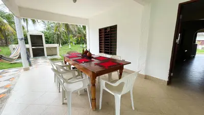 a dining room table with white chairs around it at Cabaña Villa Palmaral in Moñitos