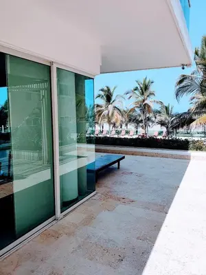 a building with a bench and palm trees in the background at Apartamento con vista frontal al mar. in Cartagena de Indias
