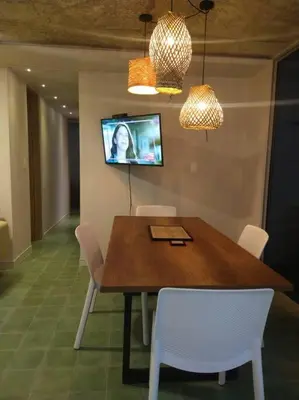 a dining room table with white chairs and a tv on the wall at Confortable apto en Coveñas in Coveñas