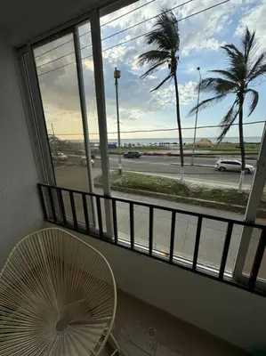 a room with a fan and a window with a palm tree at Apartamento frente a la playa in Cartagena de Indias