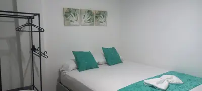 a white bed with green pillows and a picture at Shekinah House in Cartagena de Indias