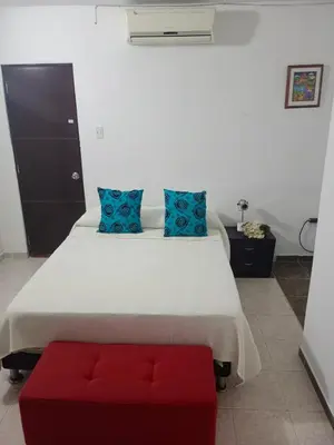 a bedroom with a large white bed with a red bench at Casa Topacio in Cartagena de Indias