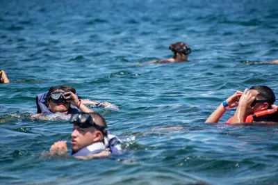 a group of people in the water taking pictures at Hotel Coral Sand Islas Del Rosario in Isla Grande