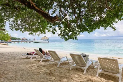 a group of people laying in lawn chairs on a beach at Hotel Coral Sand Islas Del Rosario in Isla Grande
