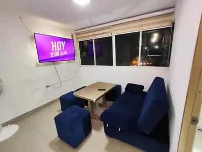 a room with a table and blue chairs and a tv at EM2-1G APARTAMENTO DE 2 HAB CERCA AL MAR ZONA RESIDENCIA WIFi Y PARQUEADERO in Cartagena de Indias