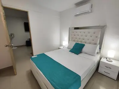 a bedroom with a large bed with a blue pillow at EM2-1G APARTAMENTO DE 2 HAB CERCA AL MAR ZONA RESIDENCIA WIFi Y PARQUEADERO in Cartagena de Indias