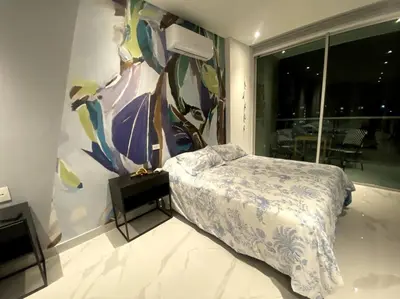 a bedroom with a bed and a painting on the wall at Espectacular apto Loft NUEVO- Frente al Hilton Pozos Colorados in Santa Marta