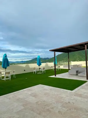 a patio with white chairs and blue umbrellas at Espectacular apto Loft NUEVO- Frente al Hilton Pozos Colorados in Santa Marta