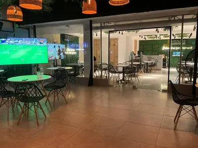 a restaurant with tables and chairs and a large screen at Hotel fenix in Barranquilla
