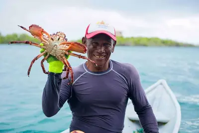 a man is holding a crab on a boat at Casa en el agua in Tintipan Island