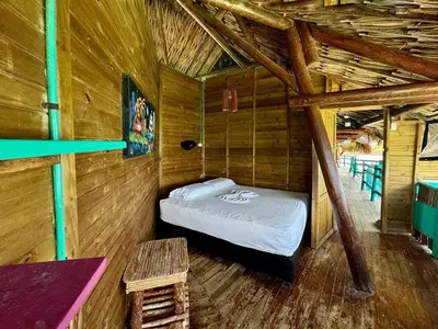 a room with a bed in a wooden cabin at Casa en el agua in Tintipan Island