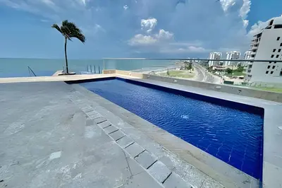 a swimming pool on the roof of a building with a palm tree at Piso 24 vista al mar 2BR in Cartagena de Indias