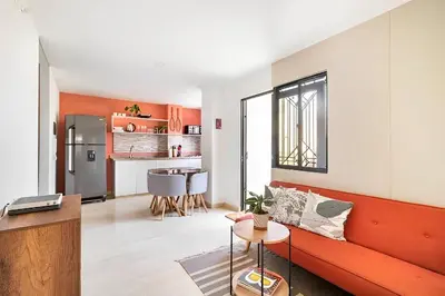 a living room with a red couch and a kitchen at Lindo apto cerca del Malecón con patio y terraza in Barranquilla