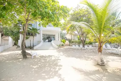 a courtyard with white chairs and trees in front of a building at Cabana Mangle Playa Privada in San Antero