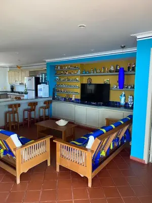 a living room with two benches and a kitchen at Condominio Playa Caimán in Coveñitas