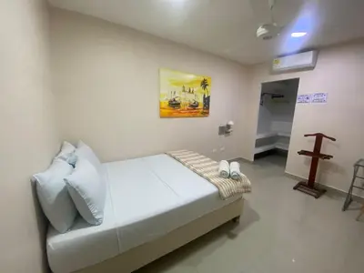 a bedroom with a bed and a cross on the wall at Casa Hotel La Niña Neyla in Cartagena de Indias