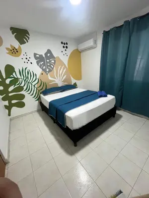 a bedroom with a bed with blue sheets and plants on the wall at Hotel Stay Golden in Cartagena de Indias