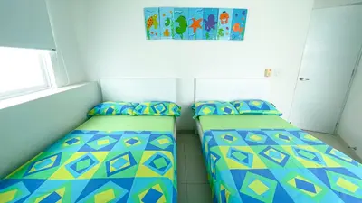 two beds in a small room with a picture on the wall at Hermoso Apartamento Frente al Mar 3 Habitaciones TR12 in Coveñitas
