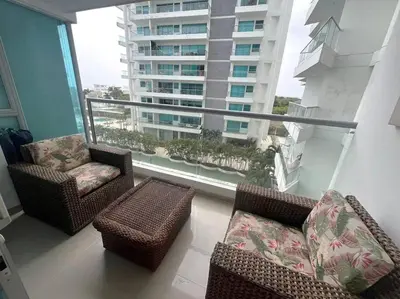 a balcony with two chairs and a couch and a large window at Amazing Beachfront Apartment in Cartagena de Indias