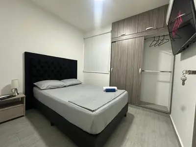 a small bedroom with a bed and a refrigerator at 3BR AC LUXURY APARTMENT CLOSE TO THE AIRPORT Beach & THE HISTORIC CENTER in Cartagena de Indias