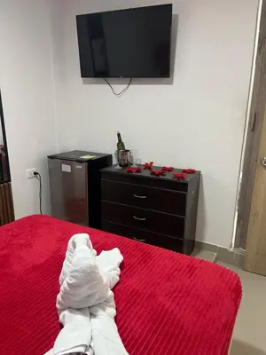 a bedroom with a red bed with a dresser and a tv at Hostel HA1 in Cartagena de Indias