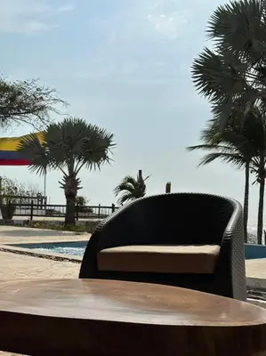 a bench sitting in front of a table with palm trees at La Mofa Beach House in Bocachica