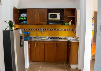 a kitchen with wooden cabinets and a microwave at Alojamiento Familiar #3 - Un terruño en la costa in Puerto Viejo