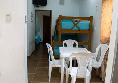 a table and chairs in a room with a bunk bed at Alojamiento Familiar #3 - Un terruño en la costa in Puerto Viejo