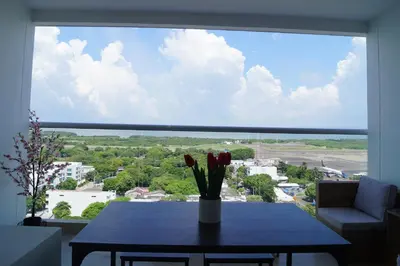 a table with a vase of flowers on a large window at Cartagena Aparta Suite Crespo Aeropuerto in Cartagena de Indias