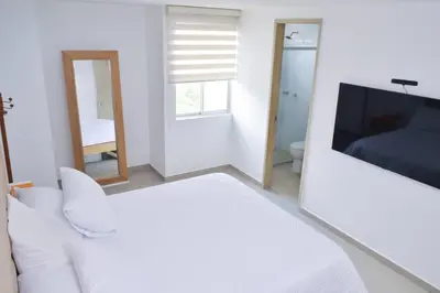 a white room with a white couch and a television at Confort en el norte de la ciudad in Ciudad Jardín