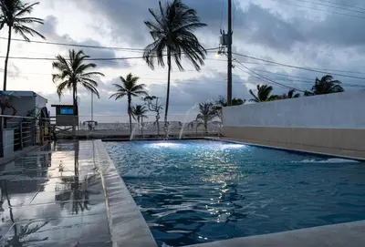 a swimming pool with palm trees in the background at Hotel Be Real in Coveñitas