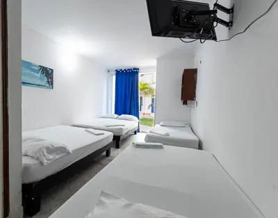 a room with three beds and a tv in it at Hotel Be Real in Coveñitas