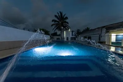a swimming pool with a fountain at night at Hotel Be Real in Coveñitas