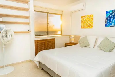 a white bedroom with a bed and a window at Apartamento frente al mar, vista al centro de Cartagena in Cartagena de Indias