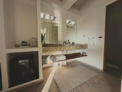 a bathroom with a fireplace and a sink and a mirror at SABAI Beach Hotel in Baru