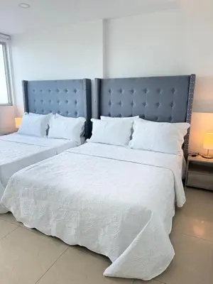 a bedroom with two beds with white blankets and pillows at Alojamiento Cartagena frente Al Mar in Cartagena de Indias