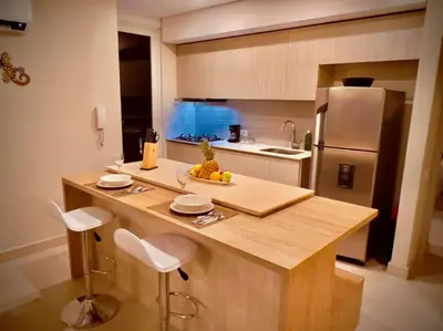a kitchen with a counter with chairs and a refrigerator at Martinique Apto Private Jacuzzi - Netflix-Disney-Prime in Cartagena de Indias