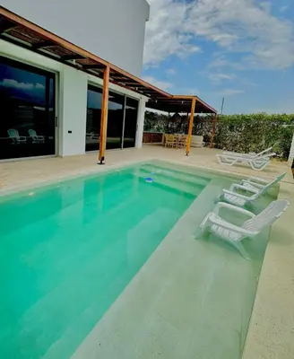 a swimming pool with two lounge chairs and a house at Casa frente a la playa in Salina de Rey