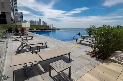 a patio with tables and benches next to the ocean at Luxury H2 piso 19 / Sea Bay View & Historic Center in Cartagena de Indias