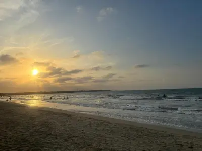 a beach with people in the ocean at sunset at Apartamento Económico En Coveñas in Coveñas